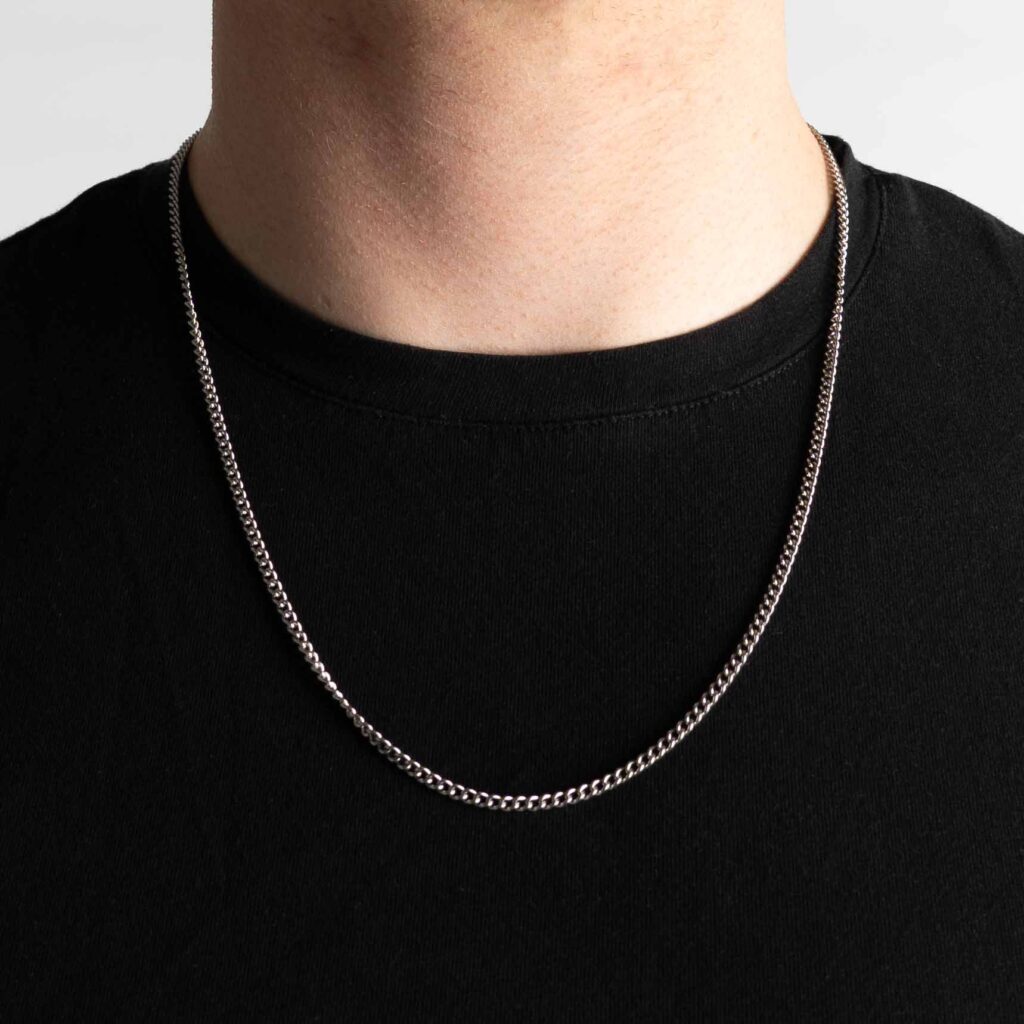 Stylish curb necklace as a fashion accessory on a man in a black t-shirt.